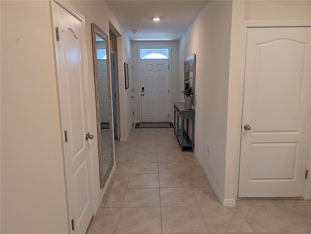 A tiled entryway features a white front door, a tall mirror, and a console table — 3329 EASTGROVE TERRACE, SANFORD, FL