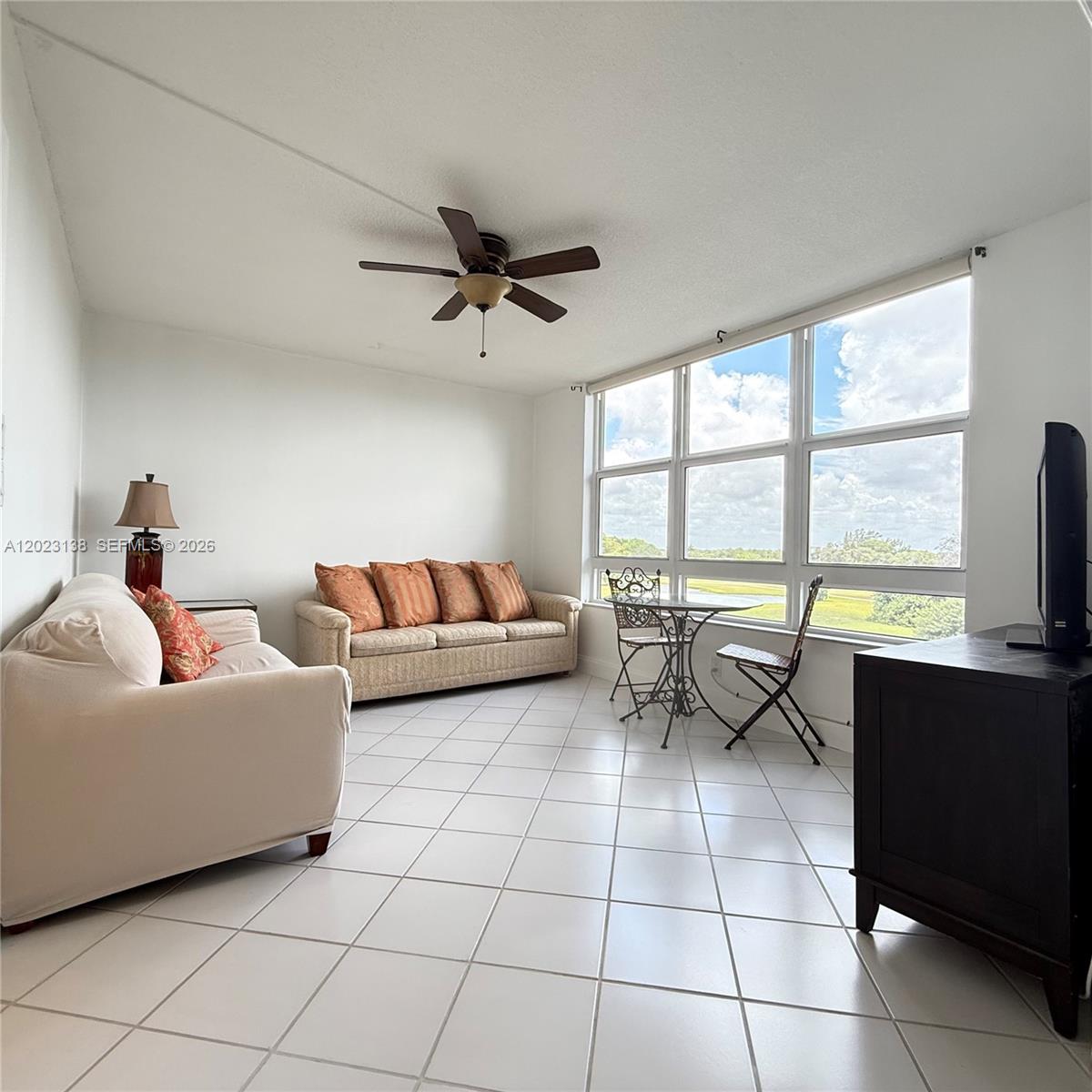 A living room features white tile floors, two sofas, a small dining set, and large windows — 2671 S Course Dr # 408, Pompano Beach FL 33069, POMPANO BEACH, FL