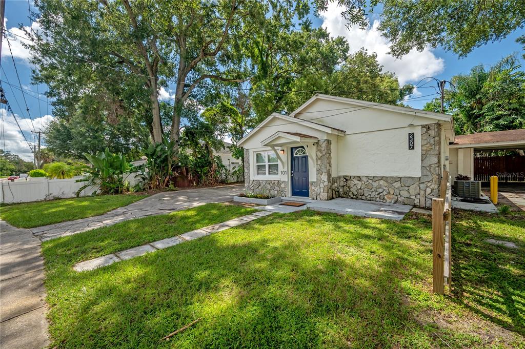 A single-story house with a stone facade, blue front door, and a paved driveway — 2307 E OSBORNE AVENUE, TAMPA, FL