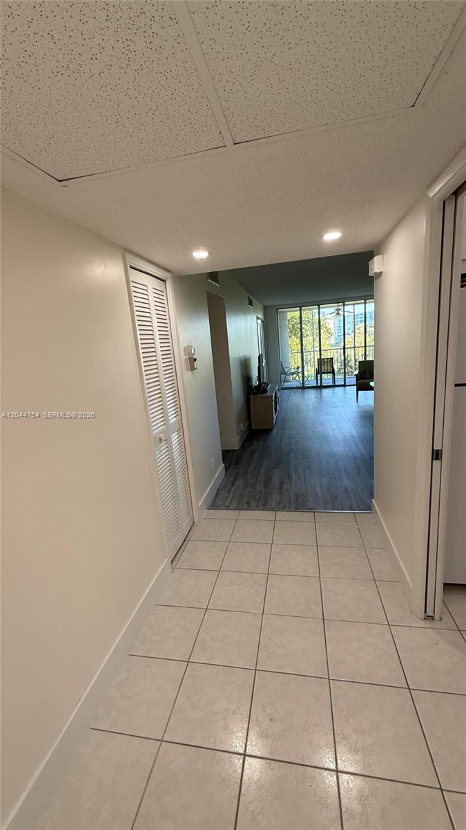 A tiled entryway leads into a living area with wood-look flooring and a balcony view — 2901 S Palm Aire Dr # 408, Pompano Beach FL 33069, POMPANO BEACH, FL