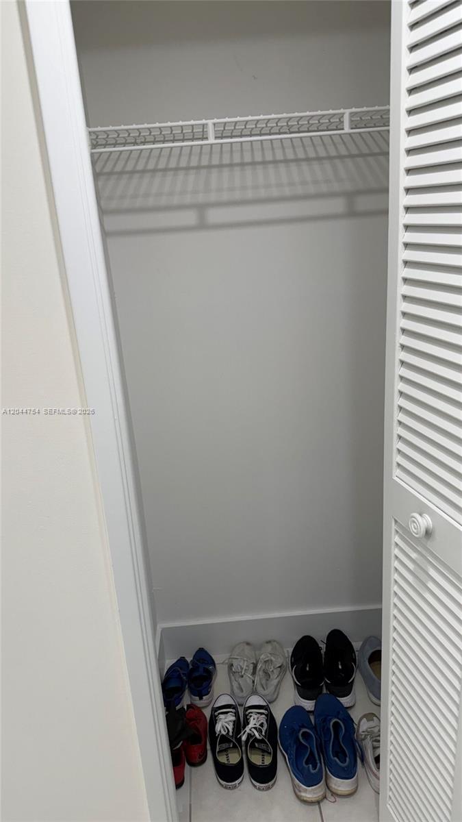 A closet with a white wire shelf and several pairs of shoes on the floor — 2901 S Palm Aire Dr # 408, Pompano Beach FL 33069, POMPANO BEACH, FL