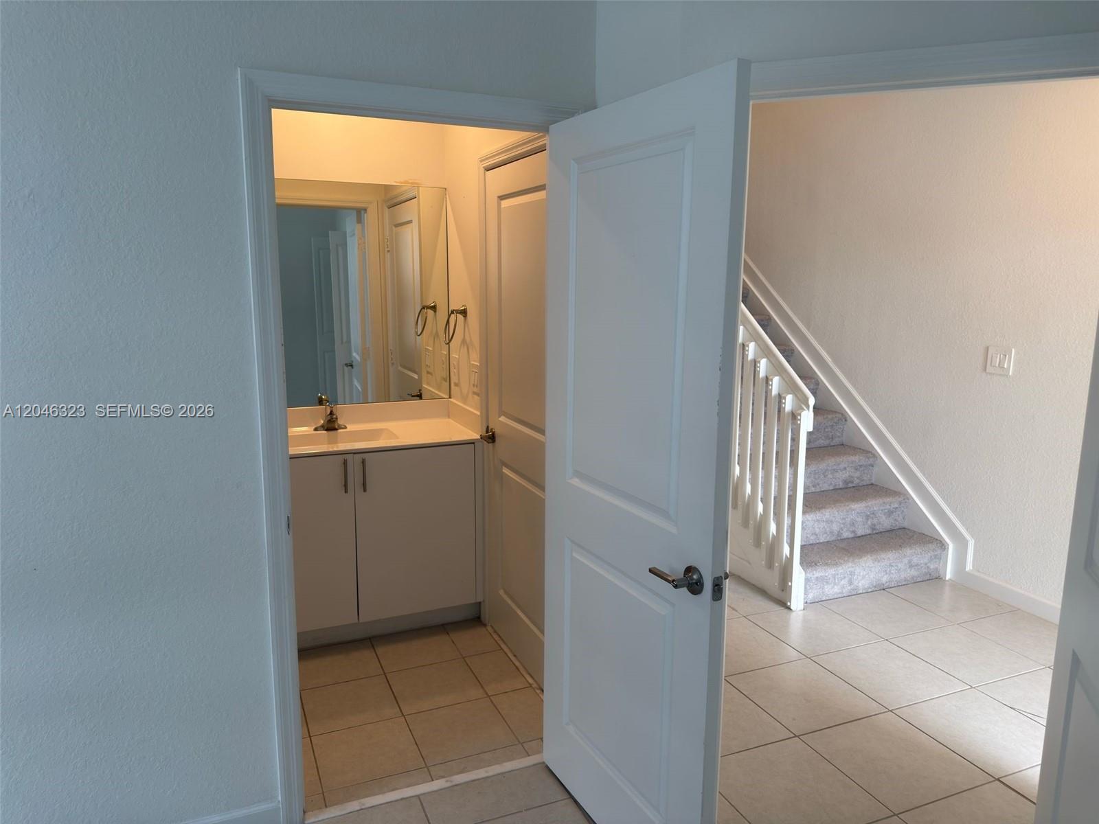 A bathroom with a vanity and mirror is visible through an open doorway near stairs — HOMESTEAD, FL