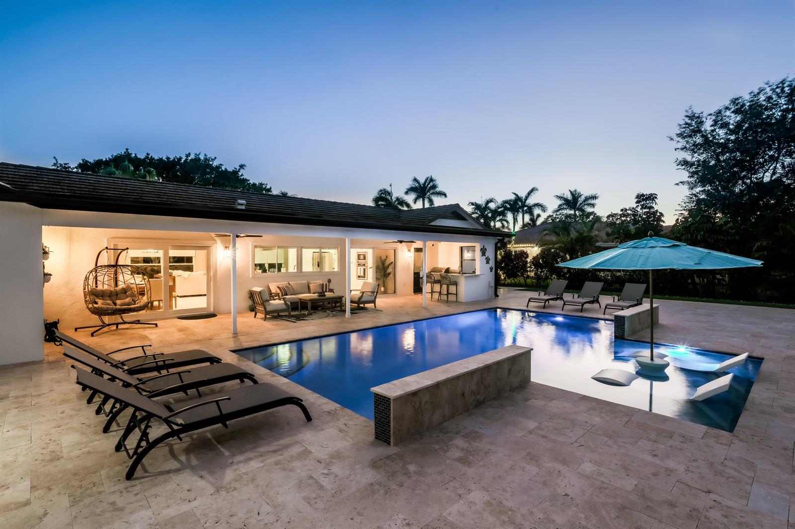 A backyard patio features a swimming pool with a tanning ledge and lounge chairs — 3127 Sherwood Boulevard, Delray Beach FL 33445, DELRAY BEACH, FL