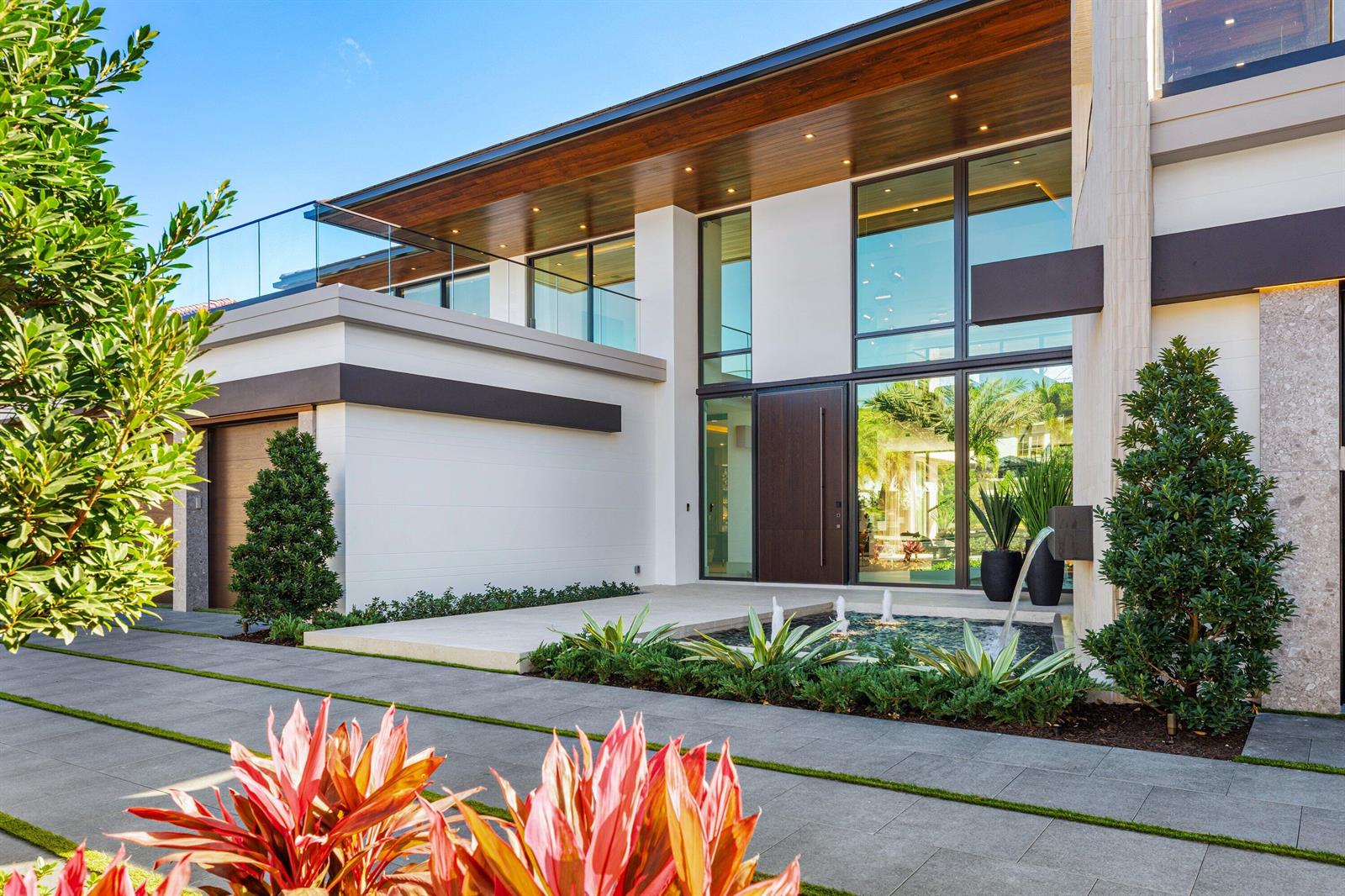 A modern two-story home features a glass balcony, a front water feature, and paved driveway — 234 W Alexander Palm Road, Boca Raton FL 33432, BOCA RATON, FL