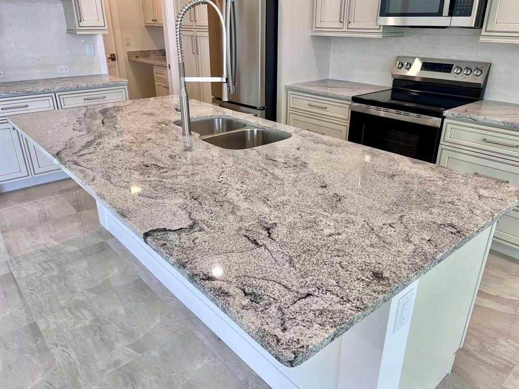 A kitchen island with a granite countertop and stainless steel sink sits in a modern kitchen — 55 ROTONDA CIRCLE, ROTONDA WEST, FL