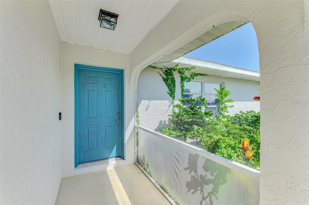 A covered entryway features a bright blue door and a screened-in porch area — 61 SHADE STREET, PORT CHARLOTTE, FL
