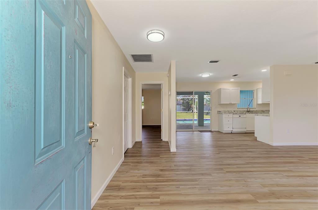 An interior view shows a light blue front door opening into a living area with wood-look flooring — 61 SHADE STREET, PORT CHARLOTTE, FL