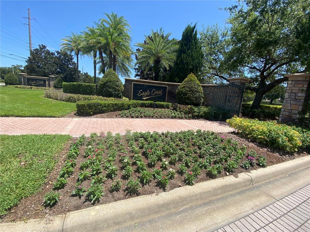 A stone monument sign for Eagle Creek stands behind a landscaped flower bed — 13324 HATHERTON CIRCLE, ORLANDO, FL