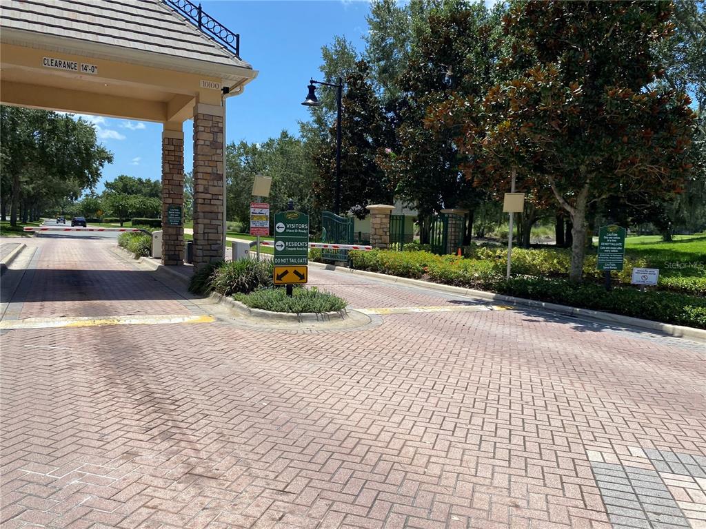 A gated community entrance features a brick-paved driveway, a security gate, and signage — 13324 HATHERTON CIRCLE, ORLANDO, FL