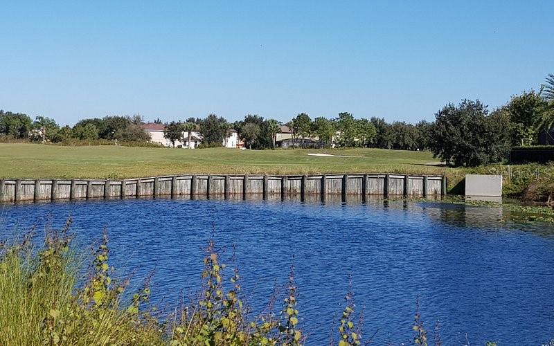 A wooden bulkhead lines the edge of a pond bordering a golf course — 13324 HATHERTON CIRCLE, ORLANDO, FL