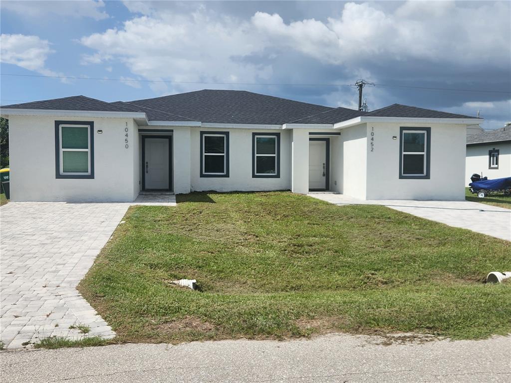 A single-story duplex with white stucco walls, dark trim, and two separate front entrances — 10450 PENDLETON AVENUE UNIT 10452, ENGLEWOOD, FL