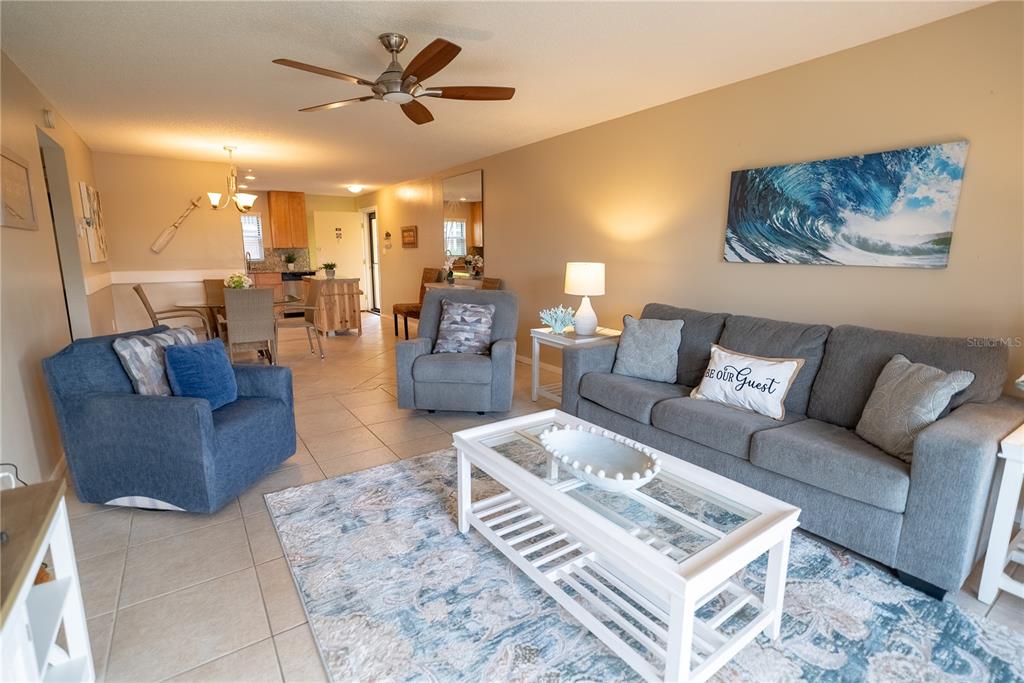 A living room with a gray sofa, blue armchair, and a white coffee table — 925 BEACH ROAD UNIT 107, SARASOTA, FL
