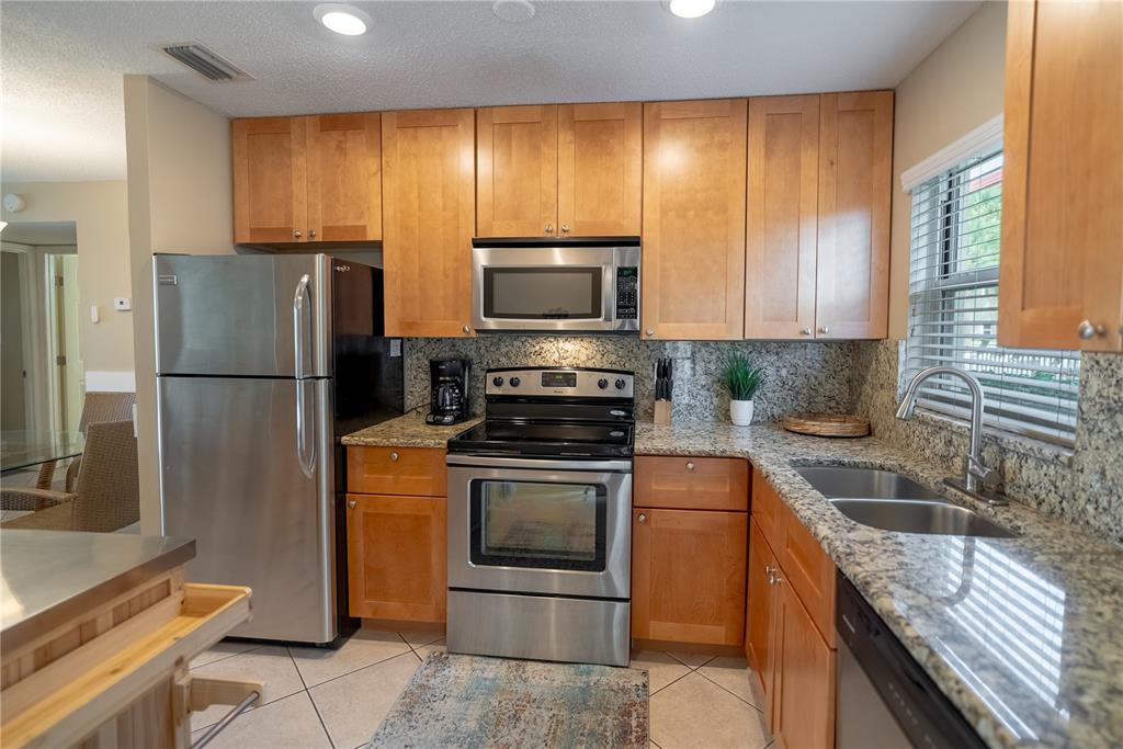 A kitchen features stainless steel appliances, light wood cabinets, and granite countertops — 925 BEACH ROAD UNIT 107, SARASOTA, FL