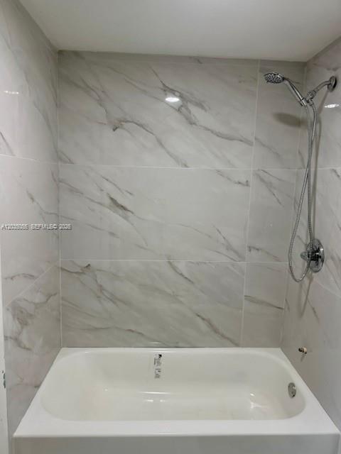 A white bathtub is set against a wall with large-format white marble-look tiles — 3640 NW 9th St # 302, Miami FL 33125, MIAMI, FL