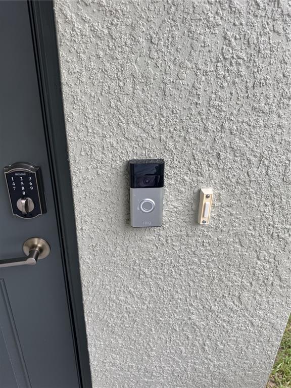 A Ring doorbell and a traditional doorbell button are mounted on a textured exterior wall — 36434 GARDEN WALL WAY, ZEPHYRHILLS, FL
