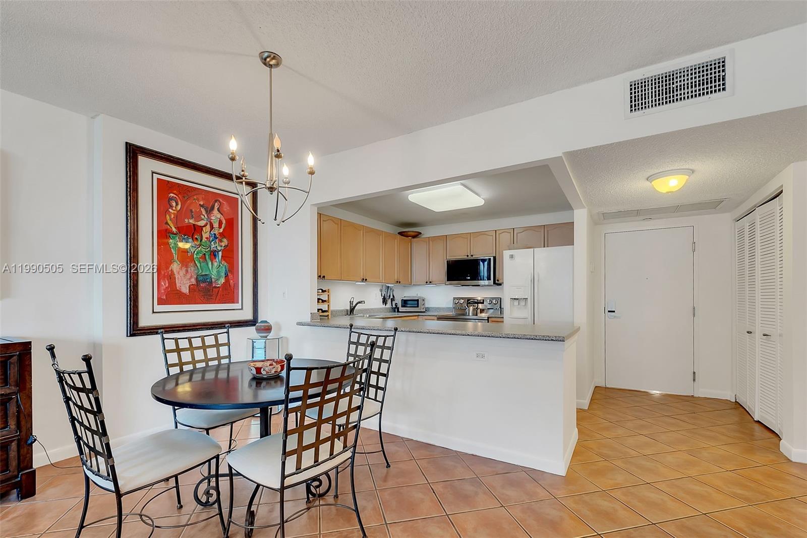 A dining area with a round table sits adjacent to an open kitchen with light-wood cabinets — 2301 Collins Ave # 533, Miami Beach FL 33139, MIAMI BEACH, FL