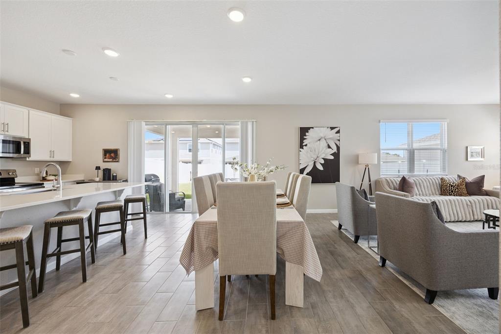 An open-concept kitchen, dining area, and living room featuring tile flooring and neutral decor — 1550 SUGARBELLE CIRCLE, MASCOTTE, FL