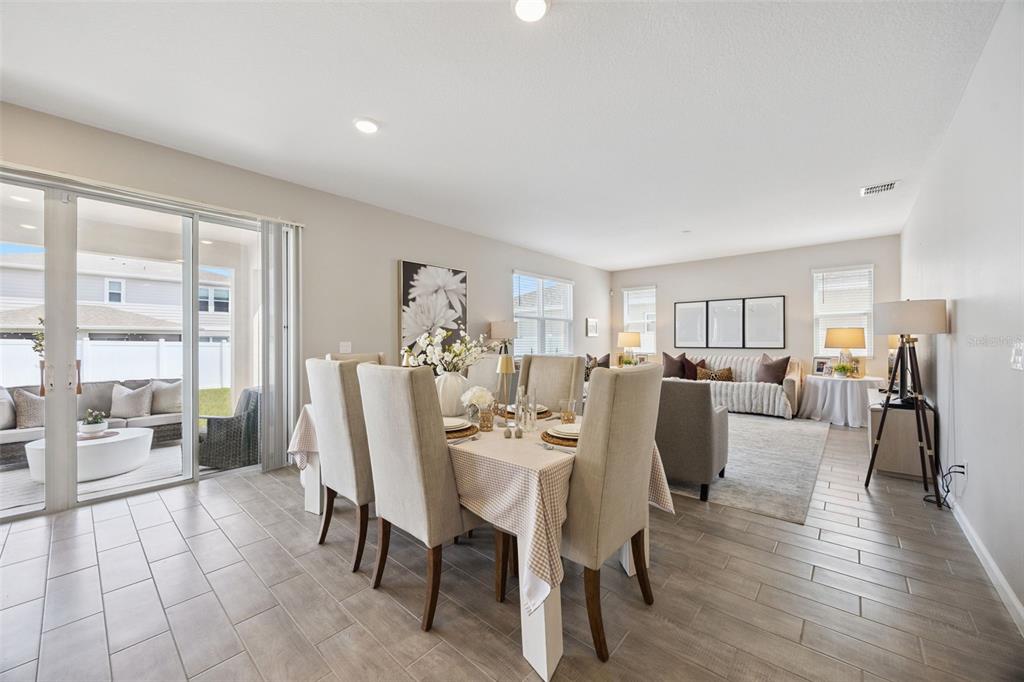 A dining area with a table and chairs opens to a patio through sliding doors — 1550 SUGARBELLE CIRCLE, MASCOTTE, FL