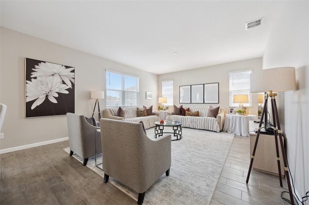 A living room features two gray armchairs, two beige sofas, and a large area rug — 1550 SUGARBELLE CIRCLE, MASCOTTE, FL