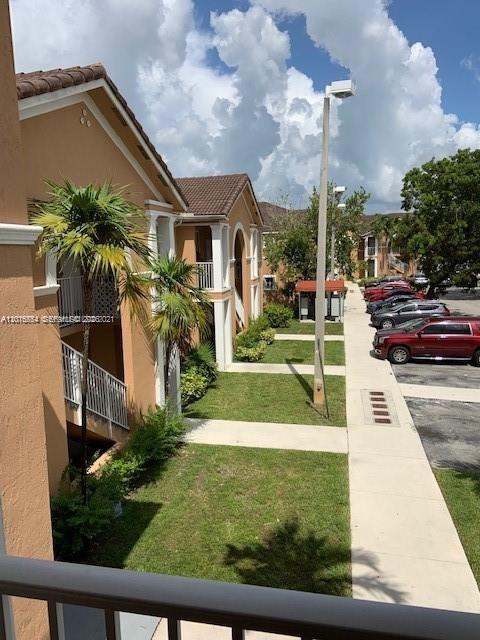 An exterior view of a multi-story apartment complex with tan walls and a sidewalk — 7100 NW 177th St # 14, Hialeah FL 33015, HIALEAH, FL