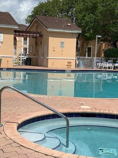 A swimming pool and hot tub are situated in front of a tan building — 7100 NW 177th St # 14, Hialeah FL 33015, HIALEAH, FL