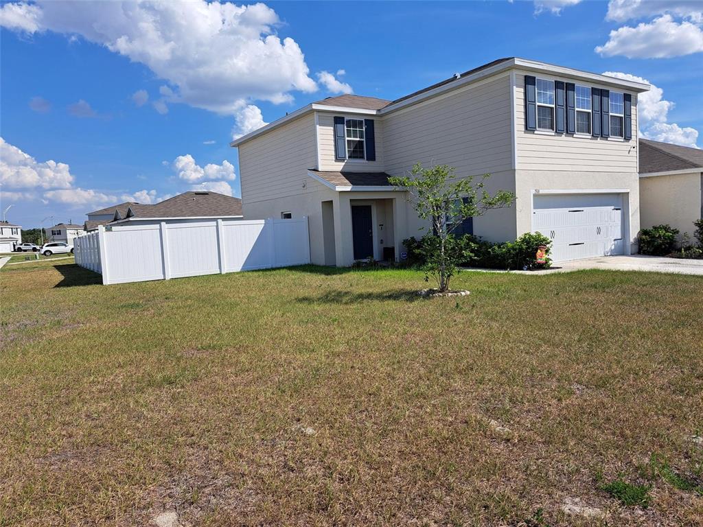 A two-story, light-colored suburban house features a white vinyl fence and a front lawn — 1508 MAJESTIC LANE, WINTER HAVEN, FL