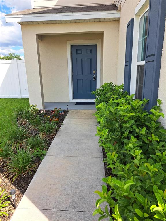 A concrete walkway leads to a blue front door under a covered entryway — 1508 MAJESTIC LANE, WINTER HAVEN, FL