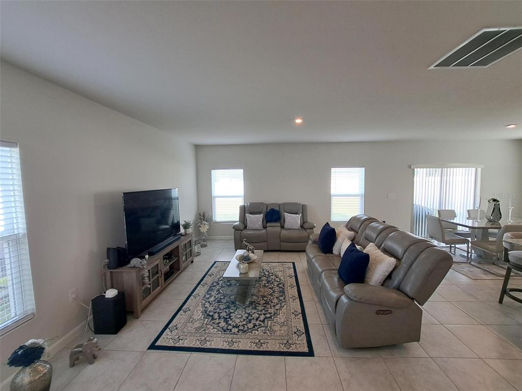 A living room features light tile floors, gray leather furniture, and a patterned area rug — 1508 MAJESTIC LANE, WINTER HAVEN, FL