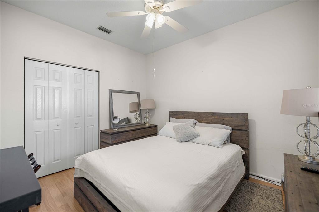 A bedroom features a wooden bed frame, a dresser with a mirror, and a ceiling fan — 2197 NW 55TH AVENUE ROAD, OCALA, FL