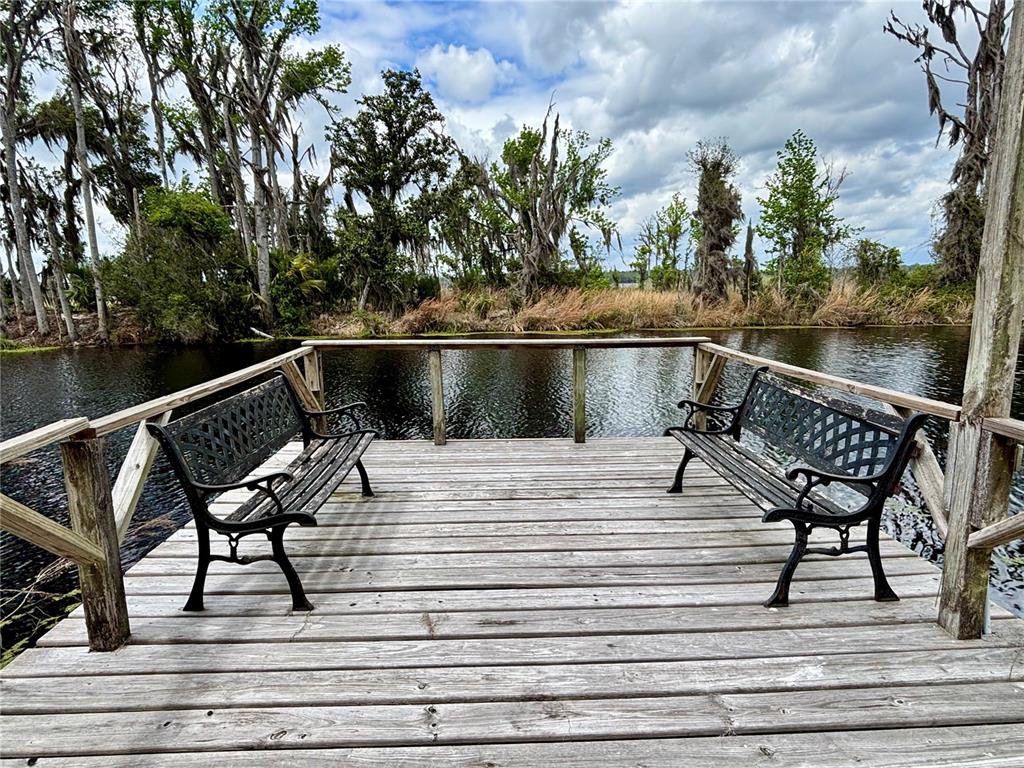 A wooden deck with two benches overlooks a calm river surrounded by trees — 216 LITTLE ORANGE LAKE DRIVE, HAWTHORNE, FL