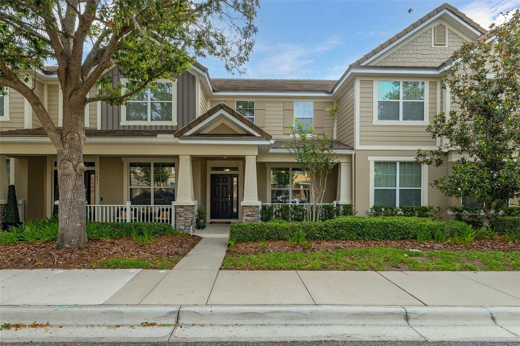 A two-story townhouse with tan siding, a covered front porch, and a landscaped front yard — 7435 RIPPLEPOINTE WAY, WINDERMERE, FL