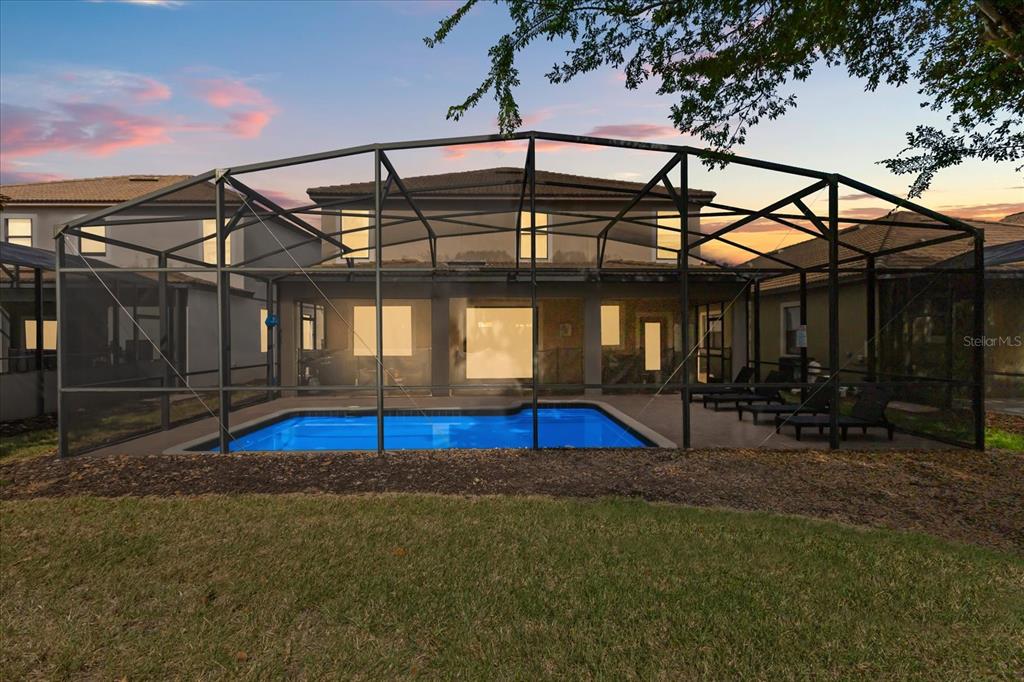A backyard view of a two-story house with a screened-in pool and patio area — 1454 MYRTLEWOOD STREET, DAVENPORT, FL