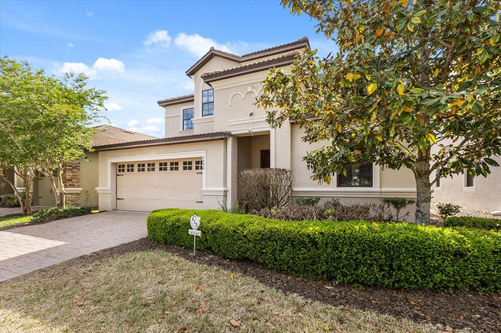 A two-story stucco house with a two-car garage and a manicured hedge in front — 1454 MYRTLEWOOD STREET, DAVENPORT, FL