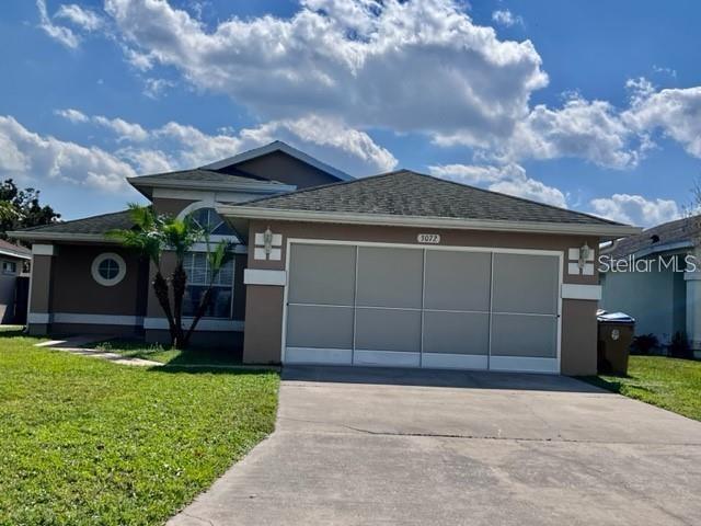 A single-story house with a tan exterior, gray roof, and a three-panel garage door — 3072 STILLWATER DRIVE, KISSIMMEE, FL