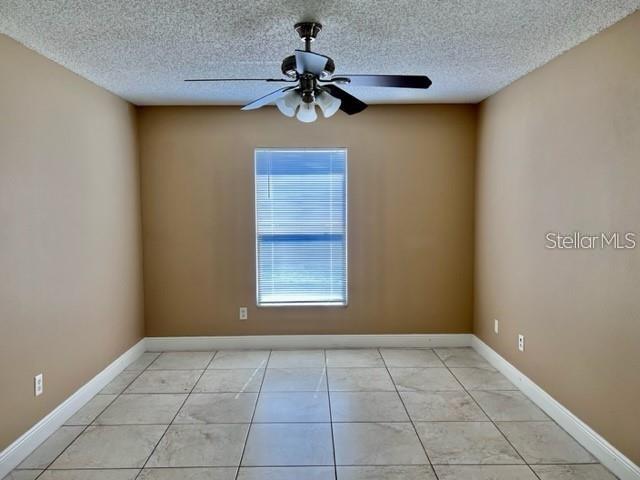An empty room with tan walls, a tiled floor, and a ceiling fan — 3072 STILLWATER DRIVE, KISSIMMEE, FL