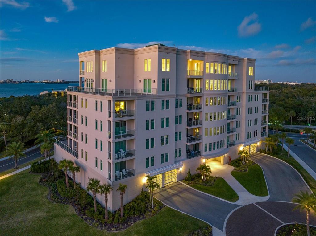 A covered balcony features outdoor furniture and a view of the water at sunset — 8 PALM TERRACE UNIT 605, BELLEAIR, FL