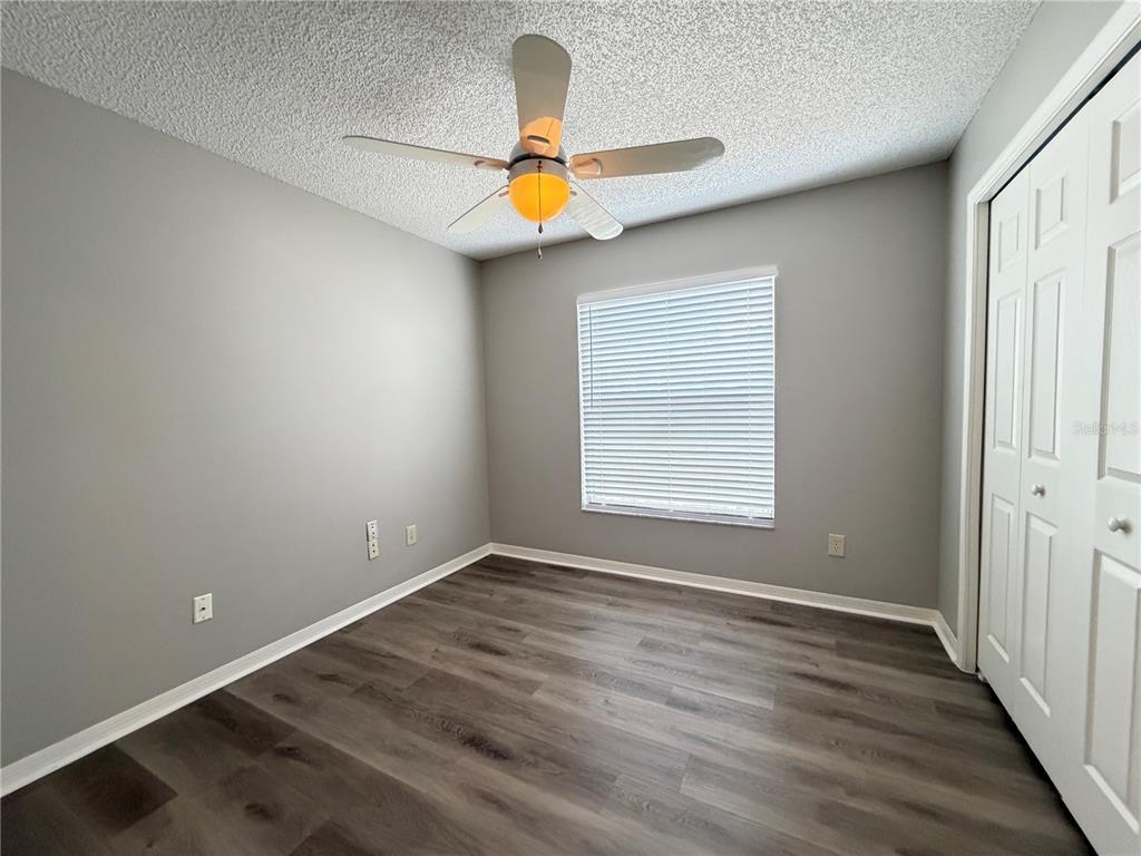 An empty bedroom features gray walls, wood-look flooring, a ceiling fan, and a white closet — 878 HIGH POINTE CIRCLE, MINNEOLA, FL