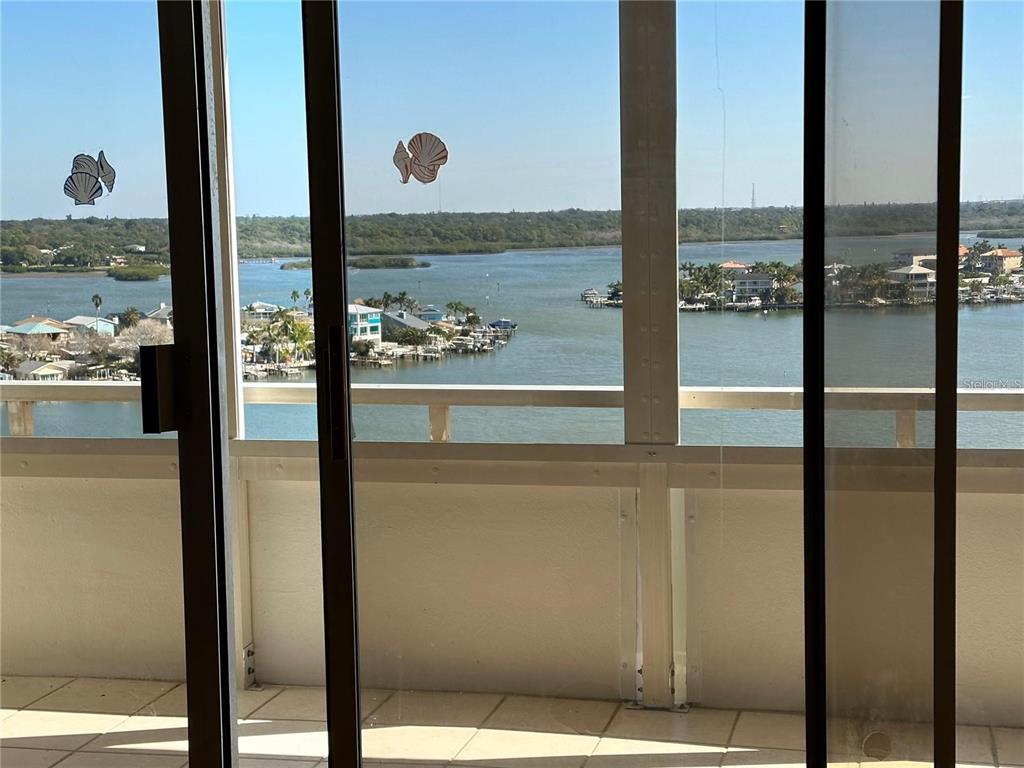 A view of a coastal waterway and houses seen through a glass balcony door — 17920 GULF BOULEVARD UNIT 1408, REDINGTON SHORES, FL