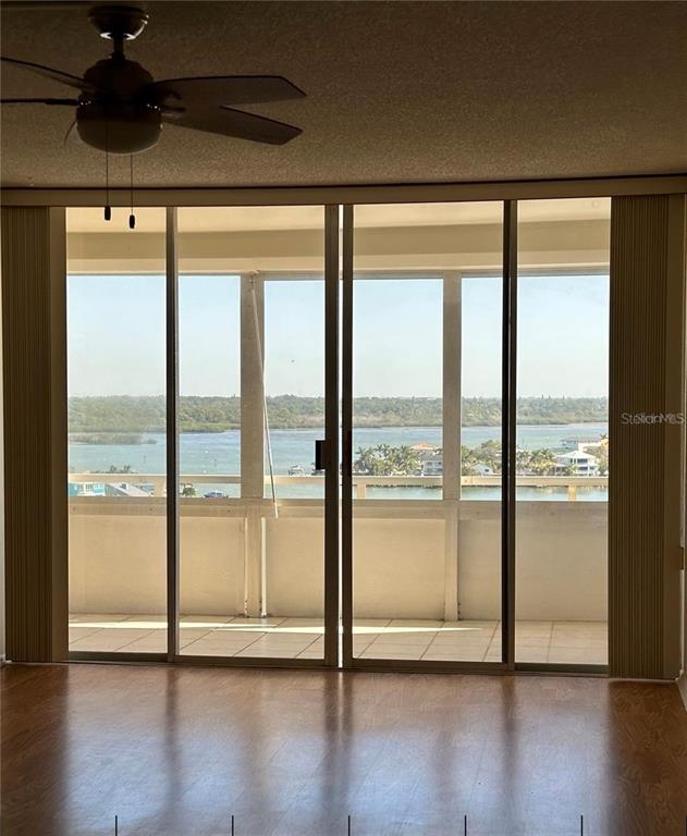 A room with wood flooring and a ceiling fan overlooks a balcony and water view — 17920 GULF BOULEVARD UNIT 1408, REDINGTON SHORES, FL