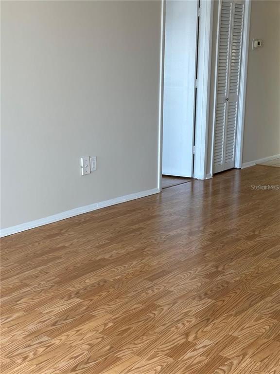 A room with light-colored walls and wood-look laminate flooring features a doorway with louvered doors — 17920 GULF BOULEVARD UNIT 1408, REDINGTON SHORES, FL