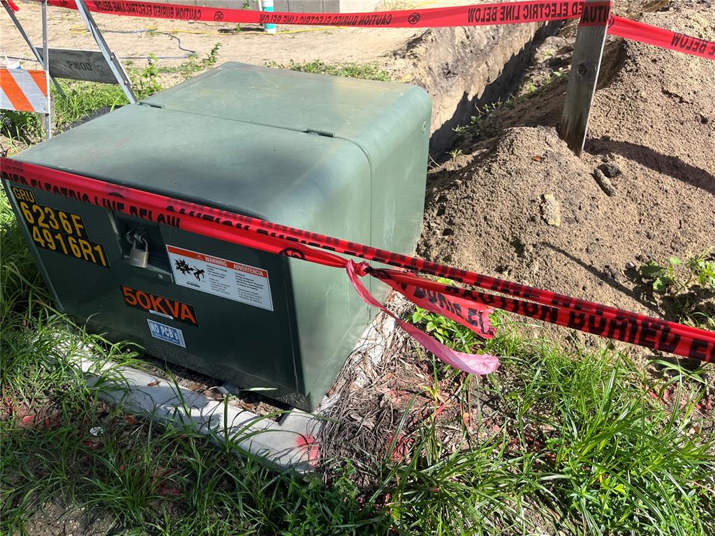 A green electrical transformer box sits next to a trench marked with caution tape — 276 NW 12TH AVE, GAINESVILLE, FL