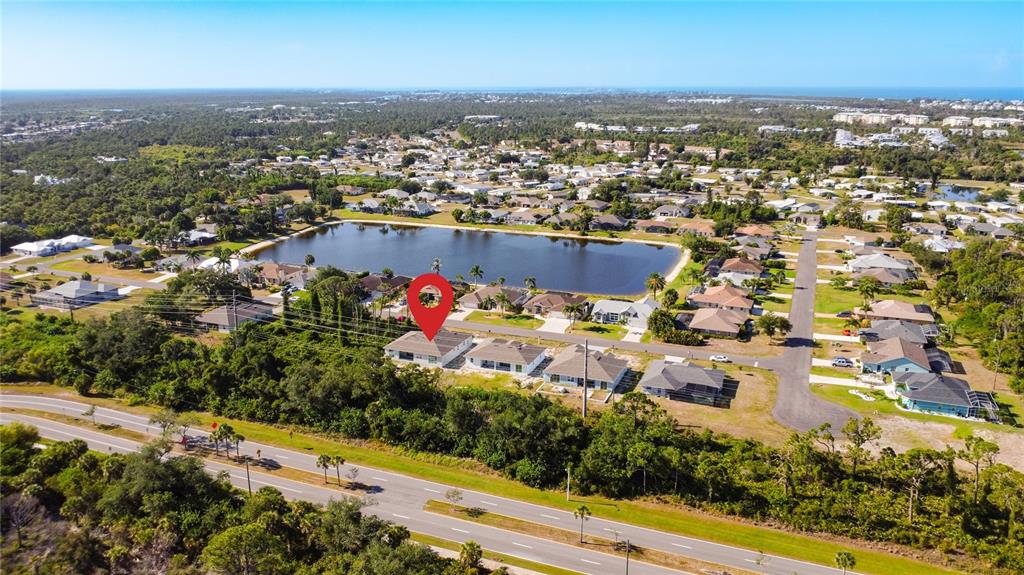 An aerial view shows a residential neighborhood with a lake and a marked house — 9040 EVELYN ROAD, ENGLEWOOD, FL
