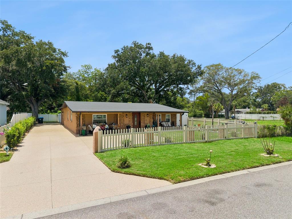 A single-story house with a tan exterior, a long driveway, and a white picket fence — 90 N GOLDWYN AVENUE, ORLANDO, FL