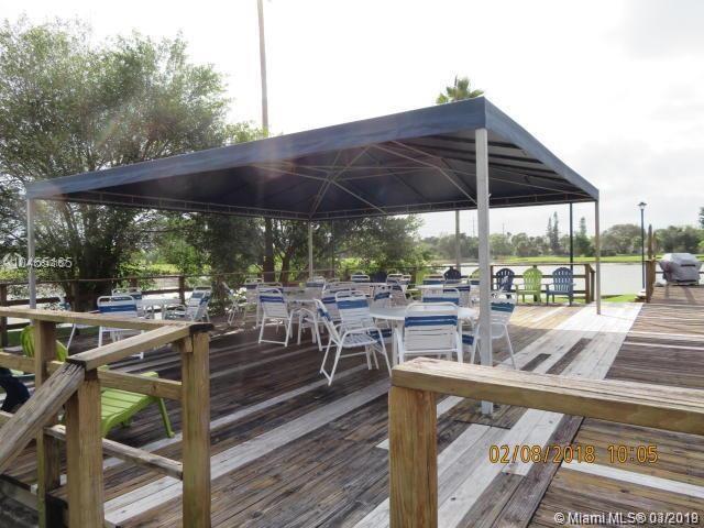 A wooden deck features a large blue canopy covering several tables and chairs near water — 4164 Inverrary Dr # 813, Lauderhill FL 33319, LAUDERHILL, FL