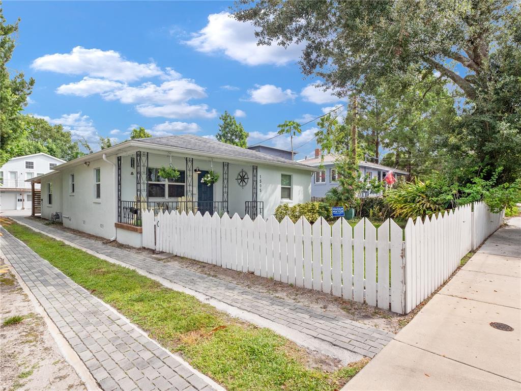 A light-colored single-story house with a white picket fence and a brick-paved walkway — 1505 CATHERINE STREET, ORLANDO, FL