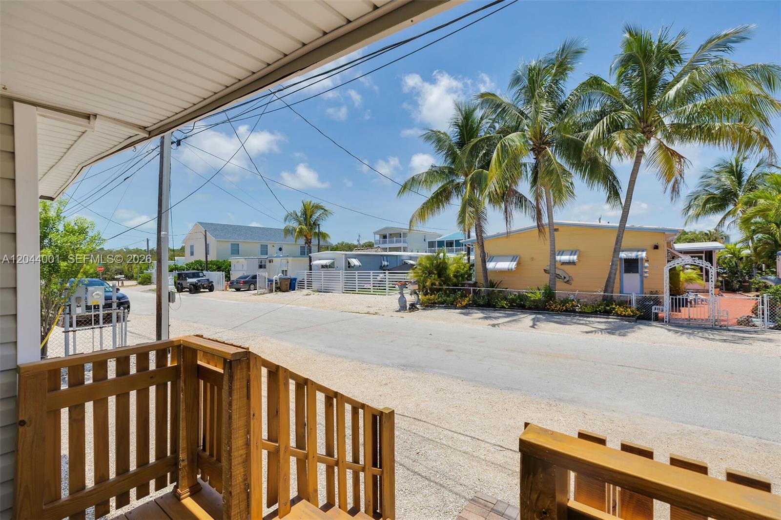 A view from a wooden porch looking out onto a street with houses and palms — 224 W 1st Ct, Key Largo FL 33037, KEY LARGO, FL