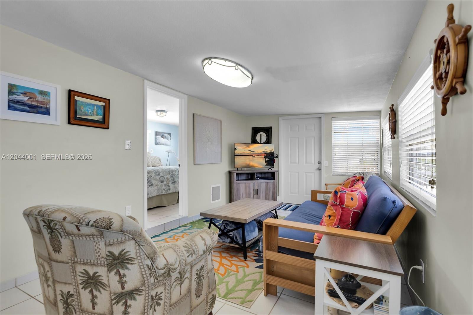 This living room features a futon, an armchair, a television, and a doorway to a bedroom — 224 W 1st Ct, Key Largo FL 33037, KEY LARGO, FL