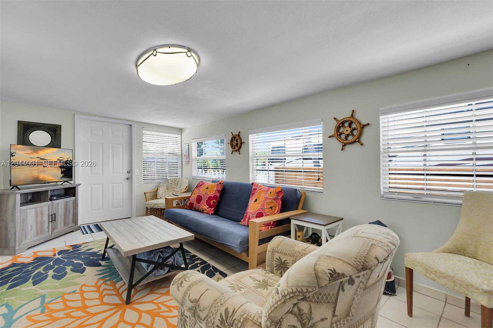 A living room features a blue futon, patterned armchair, coffee table, and nautical wall decor — 224 W 1st Ct, Key Largo FL 33037, KEY LARGO, FL