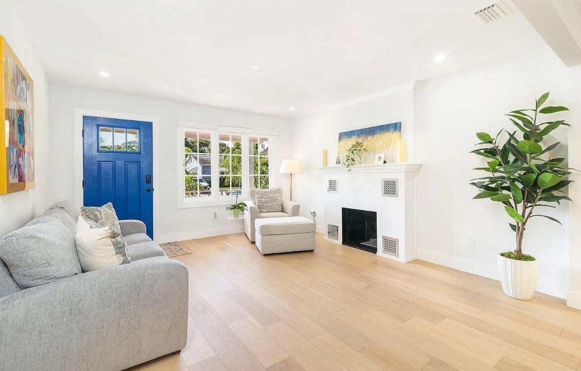 A bright living room features light wood floors, a blue front door, and a fireplace — 803 Kanuga Drive, West Palm Beach FL 33401, WEST PALM BEACH, FL