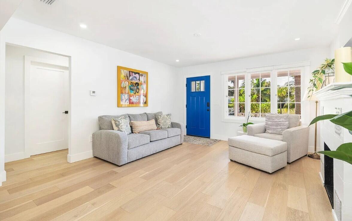 A living room features light wood floors, a grey sofa, a matching armchair, and a blue door — 803 Kanuga Drive, West Palm Beach FL 33401, WEST PALM BEACH, FL